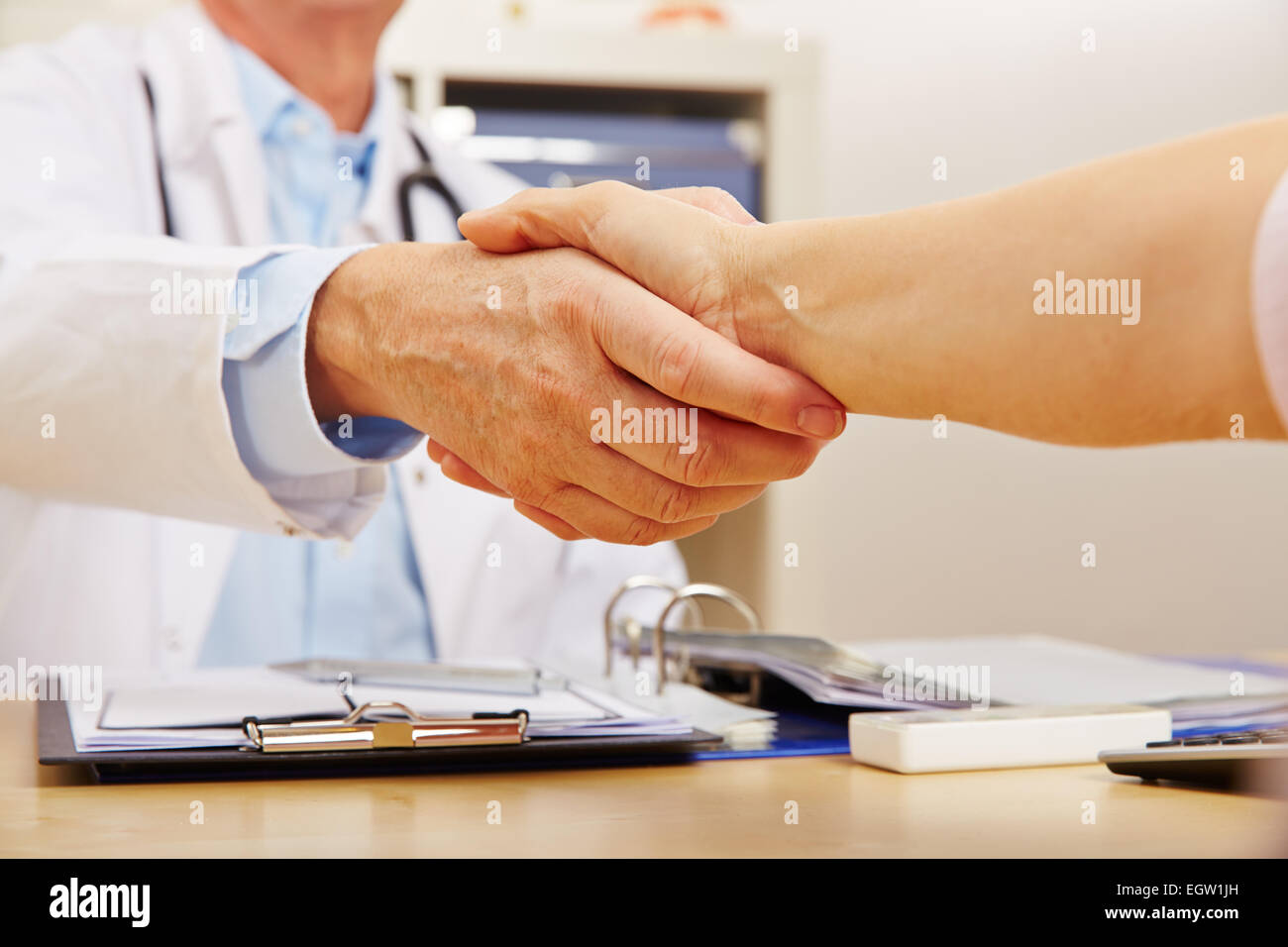 Handshake con il medico e il paziente al desk nell'ufficio del medico Foto Stock