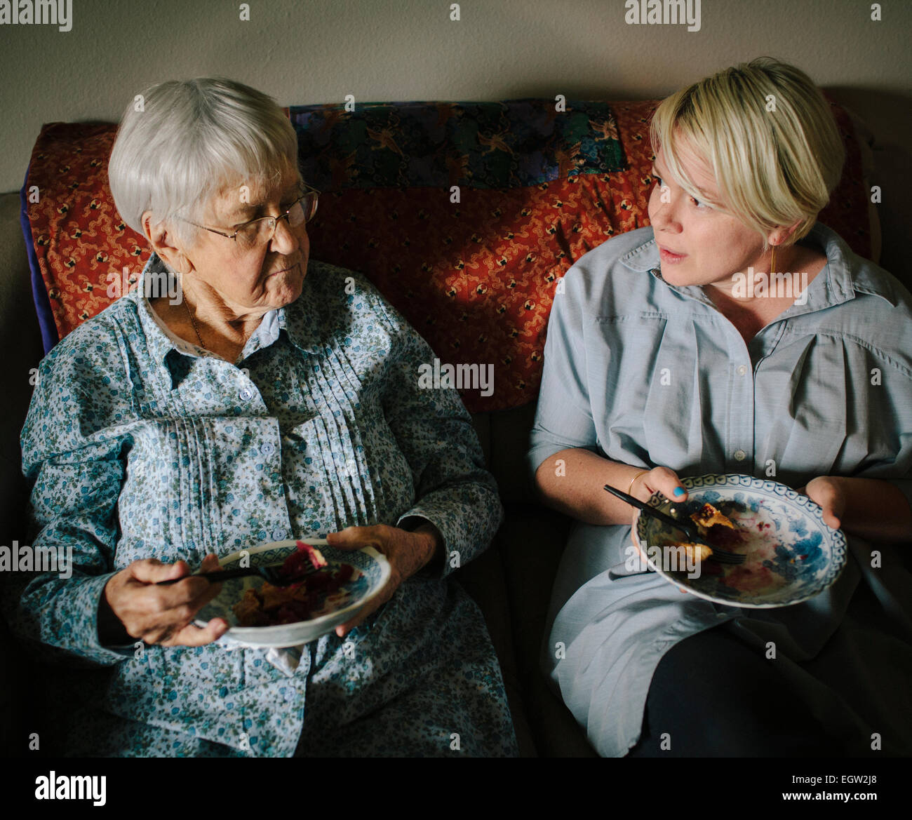 Più giovane donna e donna senior torta mangiare insieme sul divano. Foto Stock