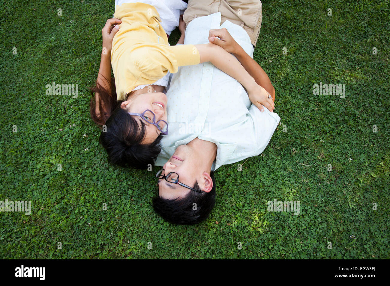 Giovane abbracciando e giacente in erba. Foto Stock