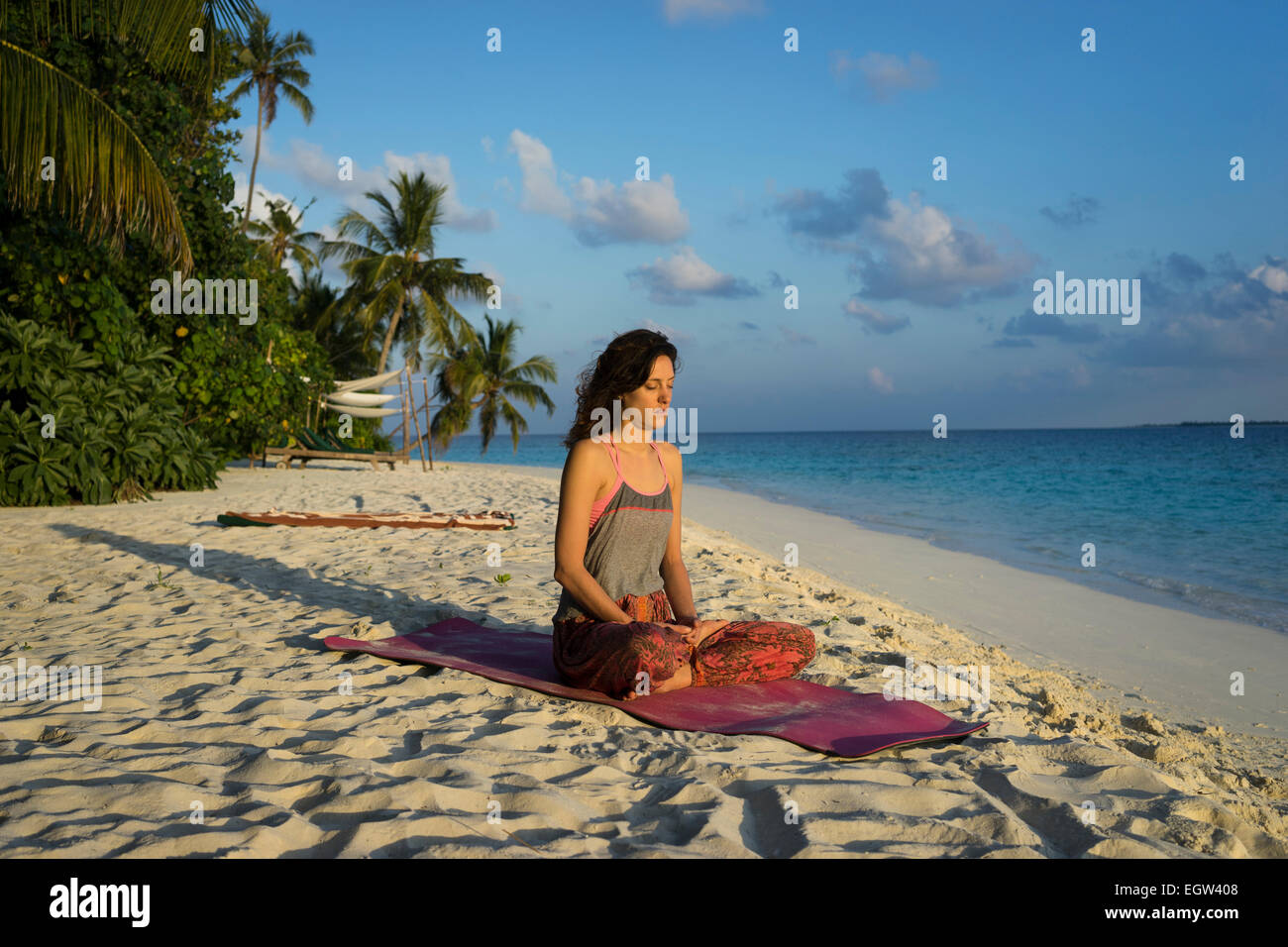 Donna meditando sulla spiaggia alle Maldive. Foto Stock