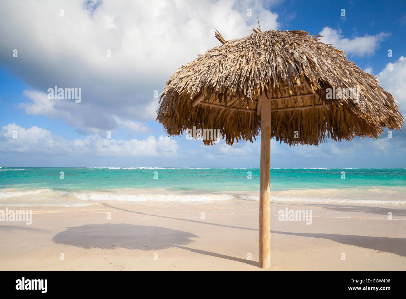 Ombrello in legno su vuoto spiaggia sabbiosa. Oceano atlantico costa, Repubblica Dominicana Foto Stock
