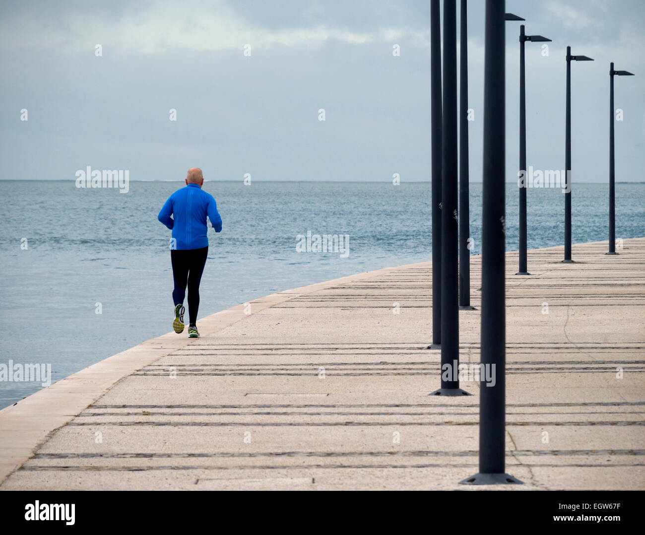 Vista posteriore di un uomo più anziano jogging da soli in riva al mare Foto Stock