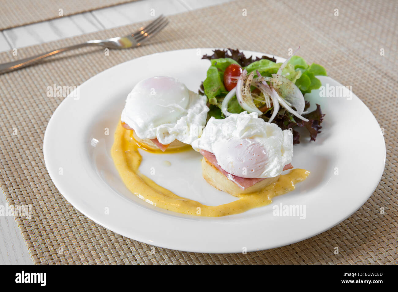 Uova Benedict- tostato muffin inglese, prosciutto, uova in camicia e burrosa deliziosa salsa olandese per la prima colazione Foto Stock