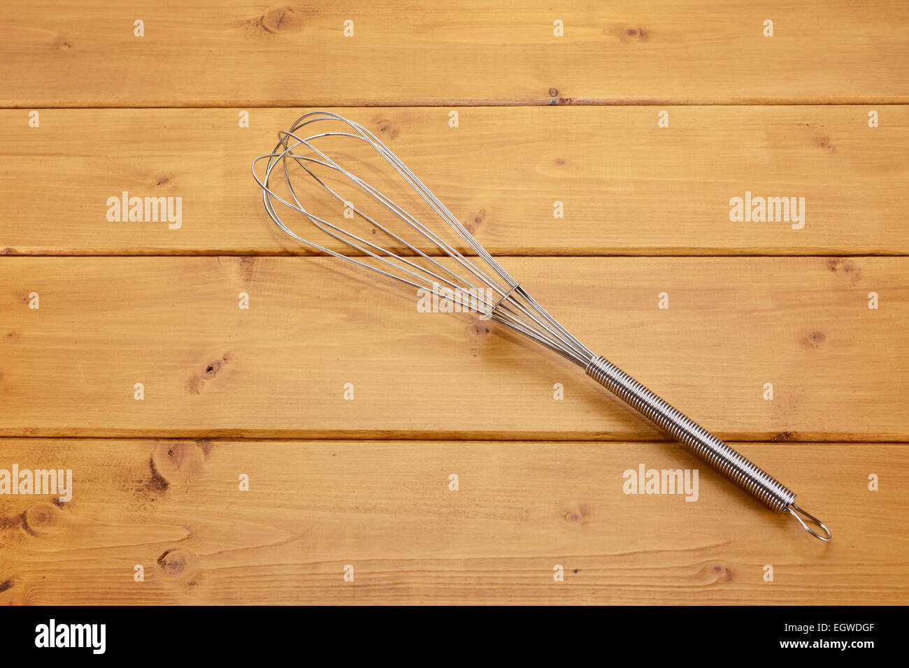 Metallo frusta a palloncino su una tavola di legno Foto Stock