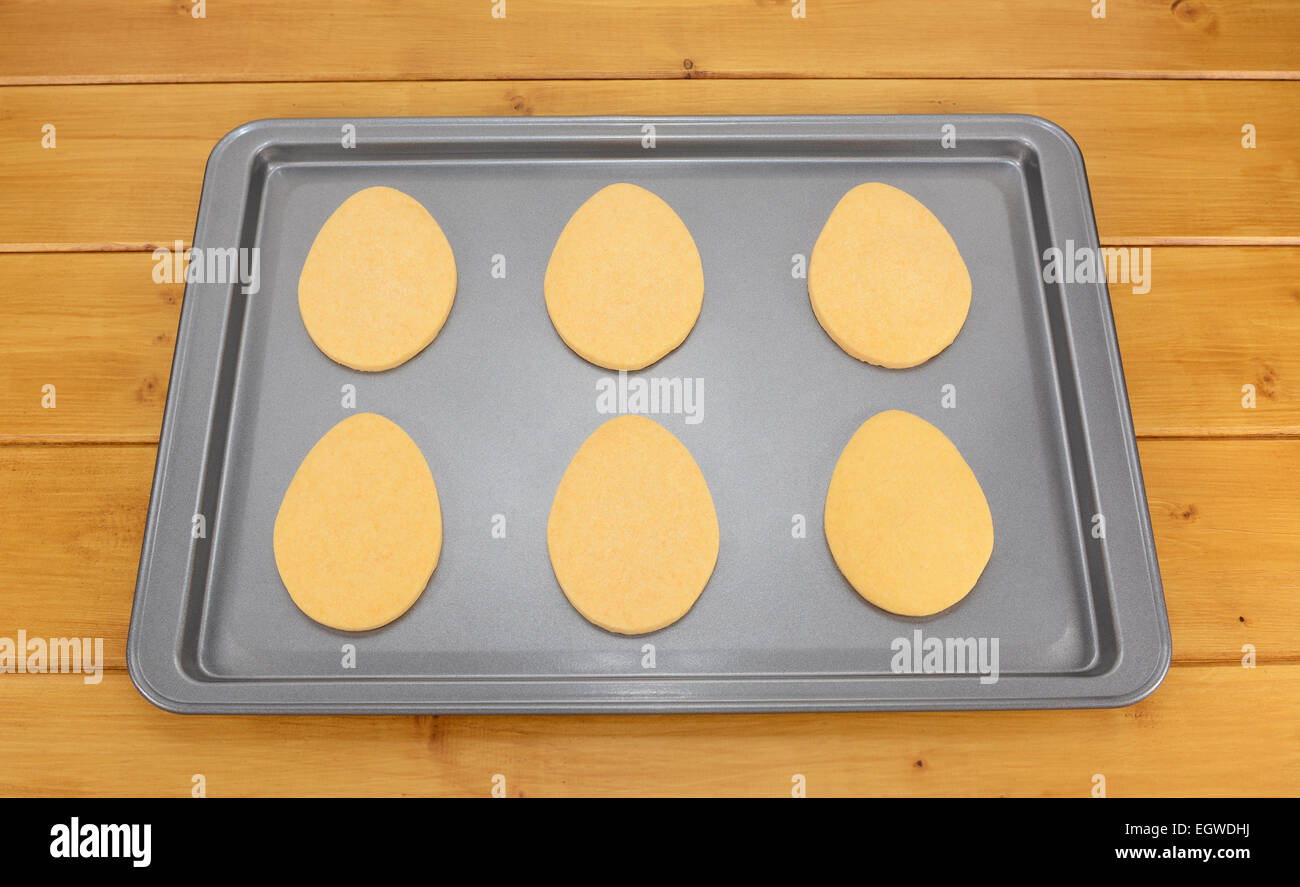 Sei a forma di uovo di pasqua i cookie su un vassoio da forno su una tavola di legno Foto Stock