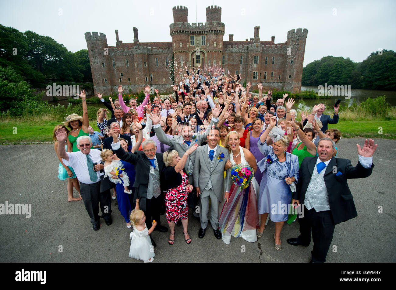 Una foto di gruppo di un matrimonio al Castello di Herstmonceux in East Sussex, Regno Unito. Tutti cheers in festa per la coppia felice. Foto Stock