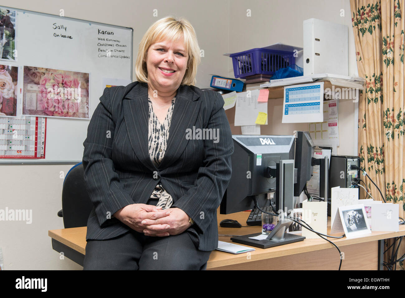 Un amministratore di business office manager dalla sua scrivania in un ambiente di ufficio impegnato la gestione dei diversi aspetti di un hotel e di un lavoro di pianificazione Foto Stock