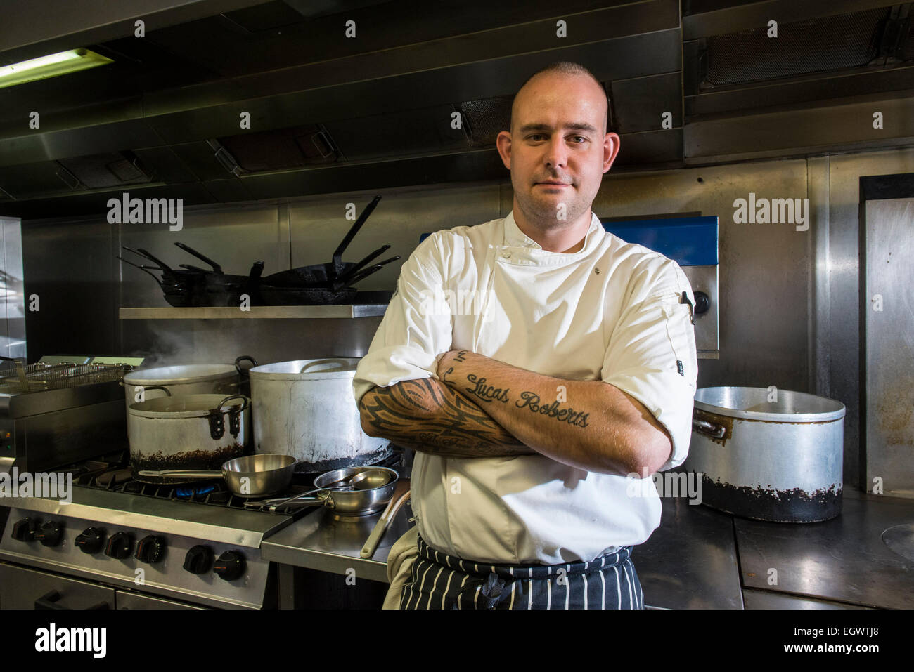 Un professionista significa ^ moody cercando chef sta nella sua cucina, guardando infastiditi con un sacco di apparecchiature di cottura in background Foto Stock