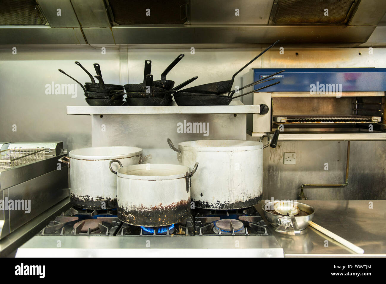 Pentole, padelle e altri utensili da cucina come spatole, coltelli, mestoli, ecc ad adornare una cucina professionale per un cuoco Foto Stock