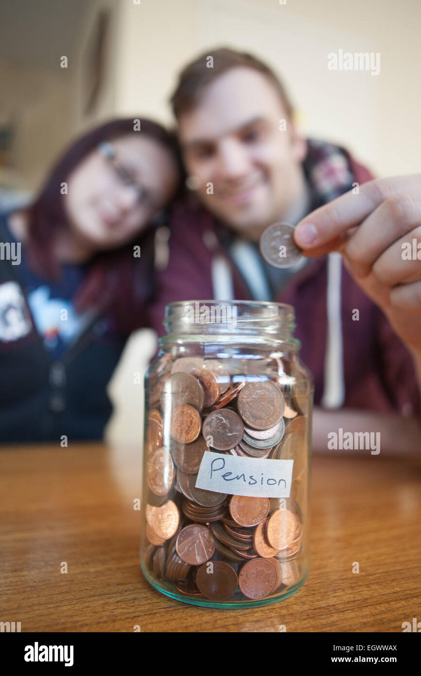 Una giovane coppia salvataggio di spiccioli per la liquidazione dei loro diritti a pensione in un vasetto di vetro. Foto Stock