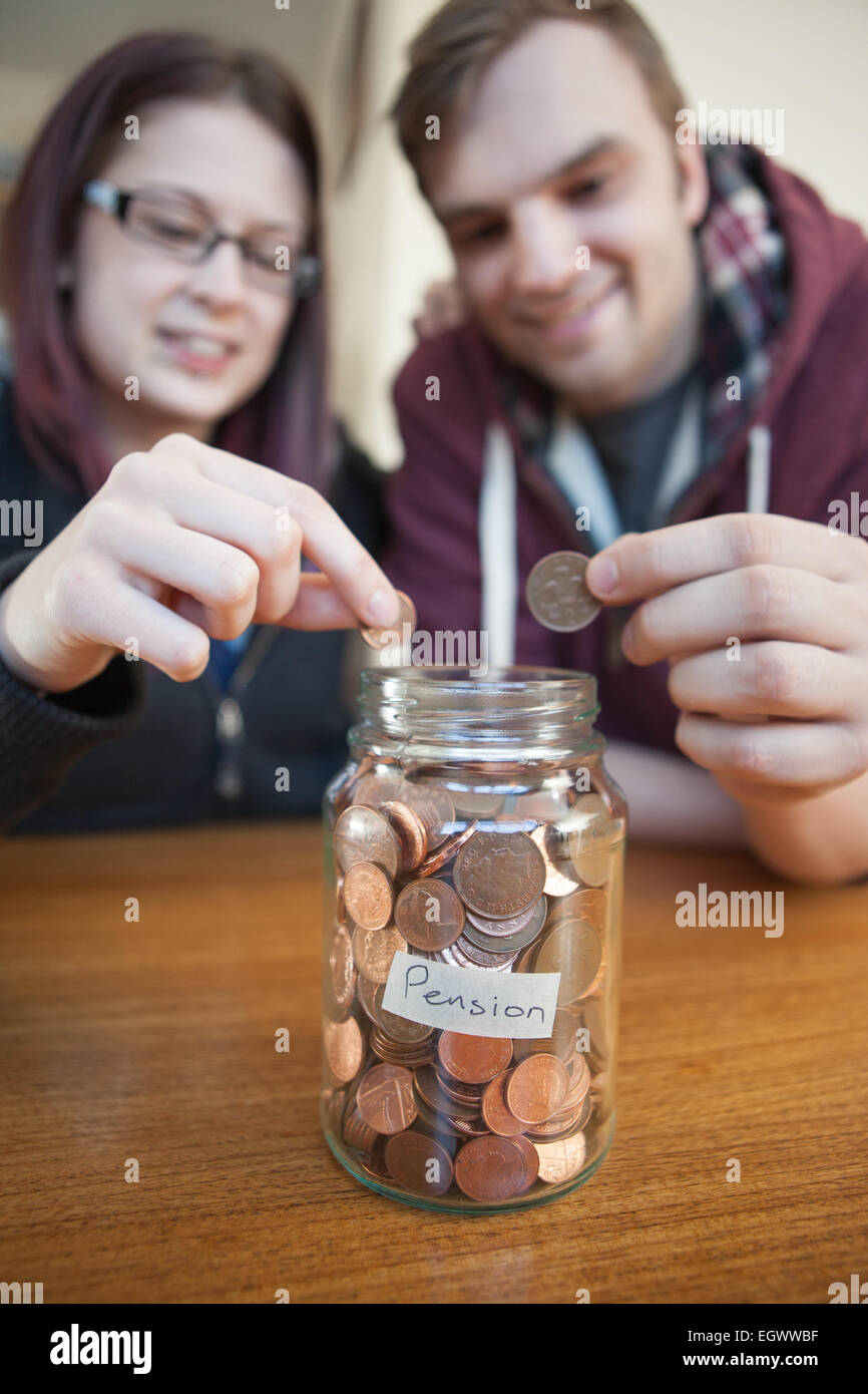 Una giovane coppia salvataggio di spiccioli per la liquidazione dei loro diritti a pensione in un vasetto di vetro. Foto Stock