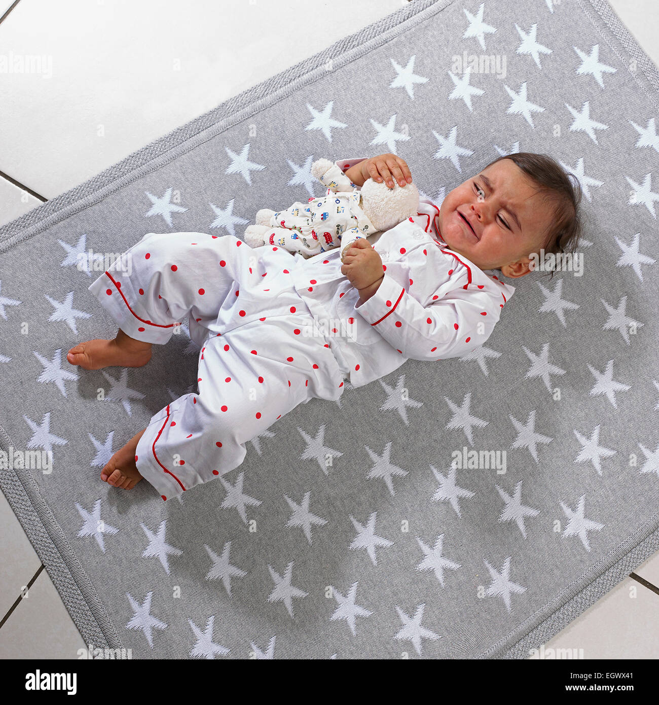Baby girl (7 mesi) giacente su una coperta tenendo un giocattolo morbido Foto Stock