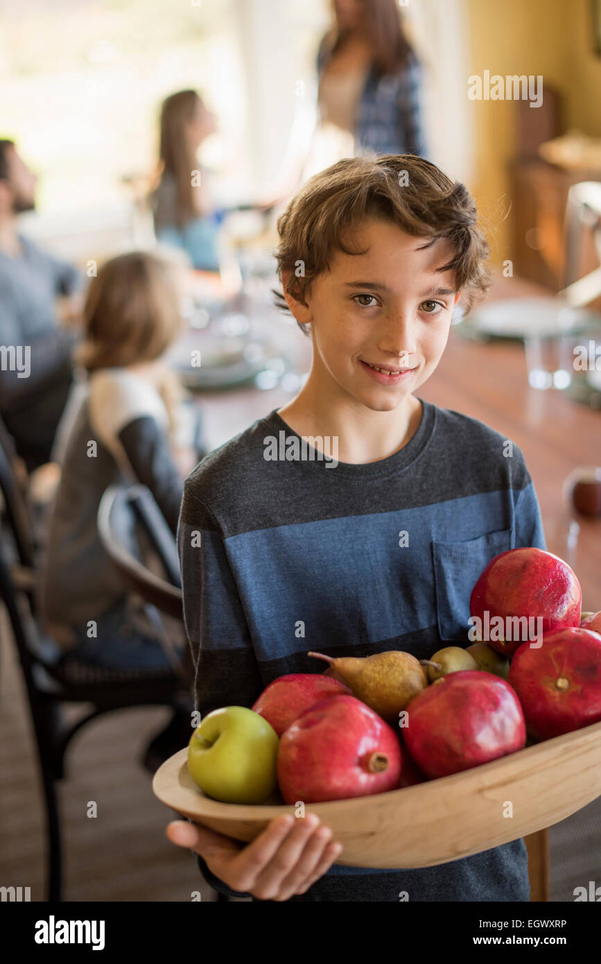 Un ragazzo carring un vassoio in legno di mele. Foto Stock