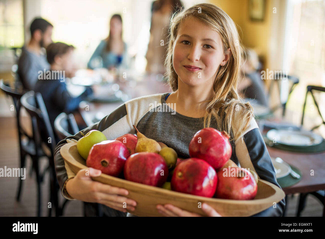 Una ragazza che porta un cesto di mele. Foto Stock