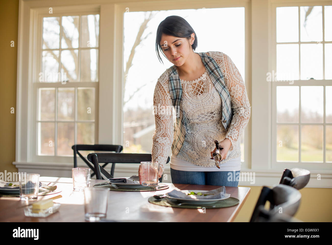 Una donna l'impostazione della tabella per un pasto. Foto Stock