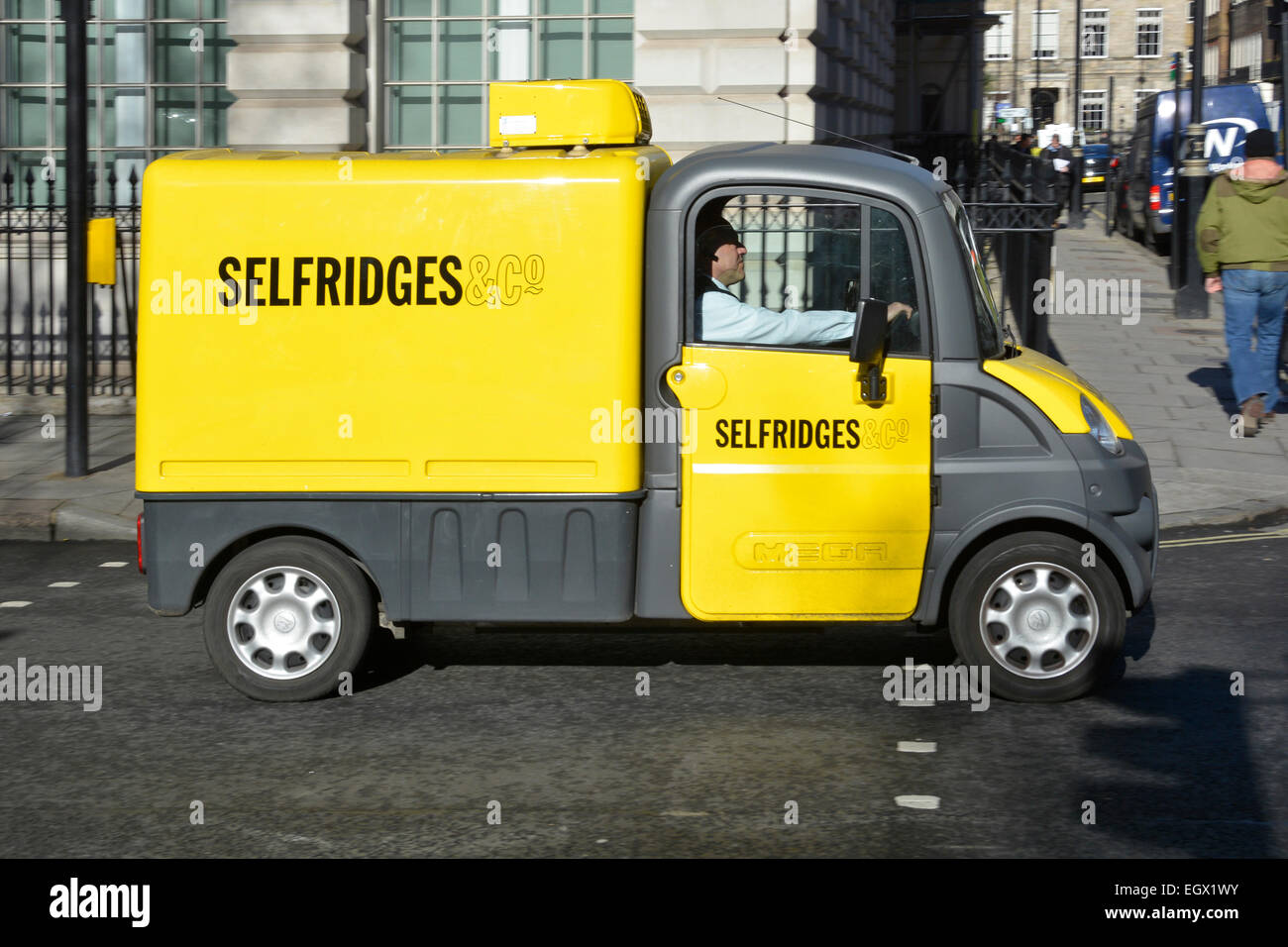 Selfridges Street scene primo piano piccolo giallo Aixam Mega van e conducente giornata di sole nel West End Londra Inghilterra Regno Unito Foto Stock