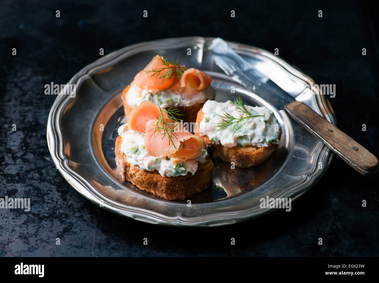 Crostini con salmone affumicato e crema di formaggio spalmabile su vintage piastra di metallo messa a fuoco selettiva Foto Stock