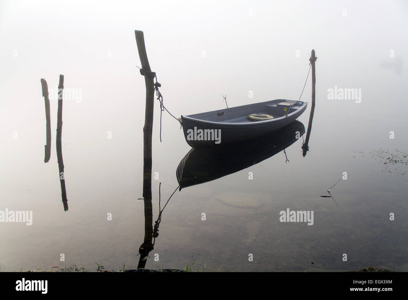 Barca da pesca nel lago con la nebbia Foto Stock