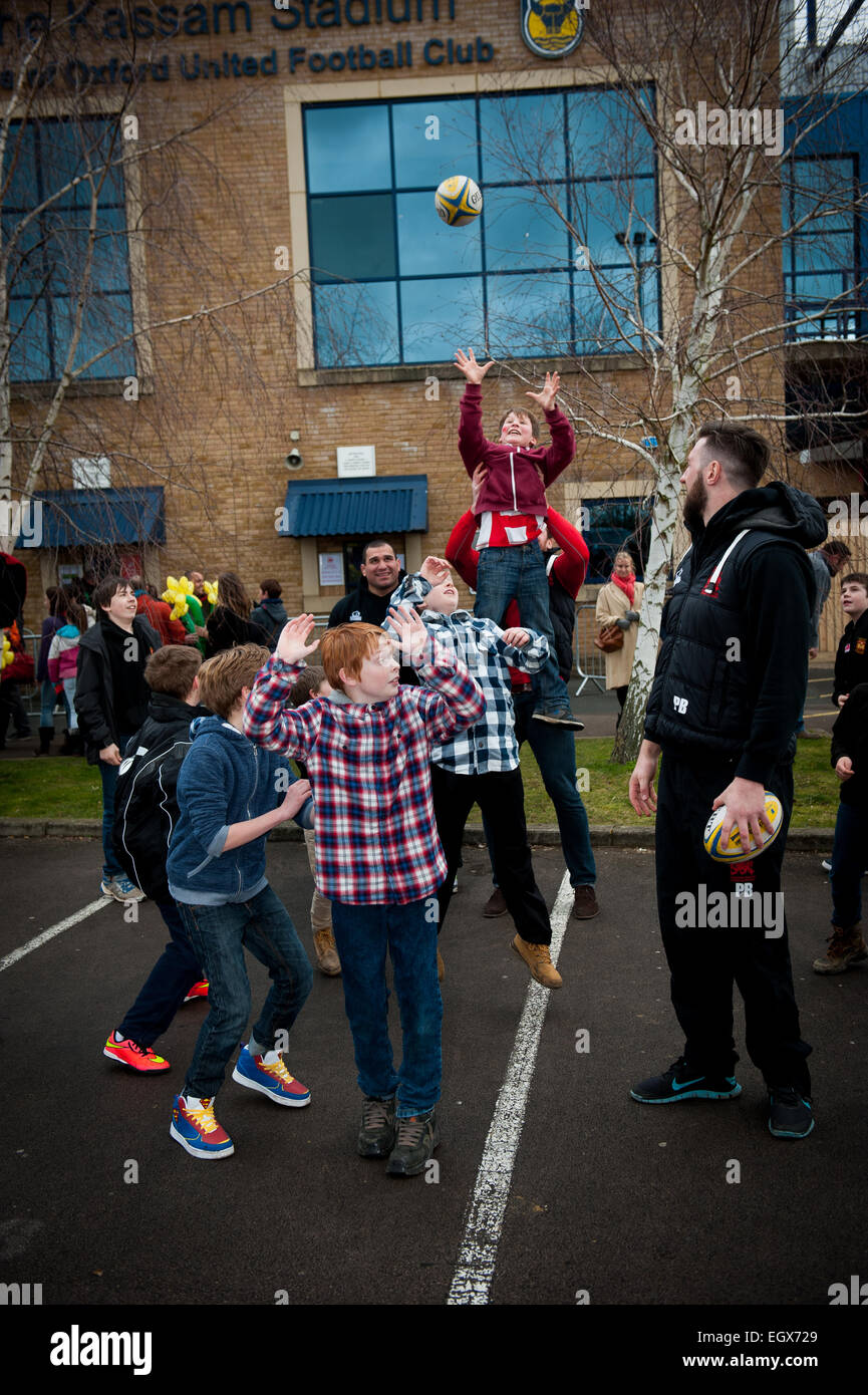 Bambini locali fare una linea di rugby con giocatori da London Welsh Rugby ai Kssam Stadium Foto Stock