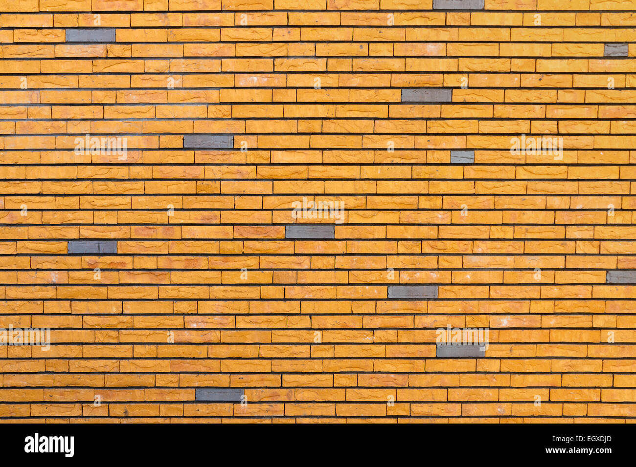 Mattone giallo a parete con superficie irregolare intervallati con alcuni mattoni grigio Foto Stock