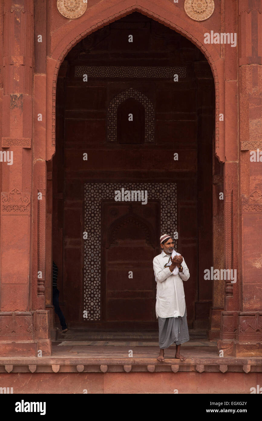 Uomo musulmano in piedi sotto un arco a sesto acuto in Fatehpur Sikri, Uttar Pradesh, India Foto Stock