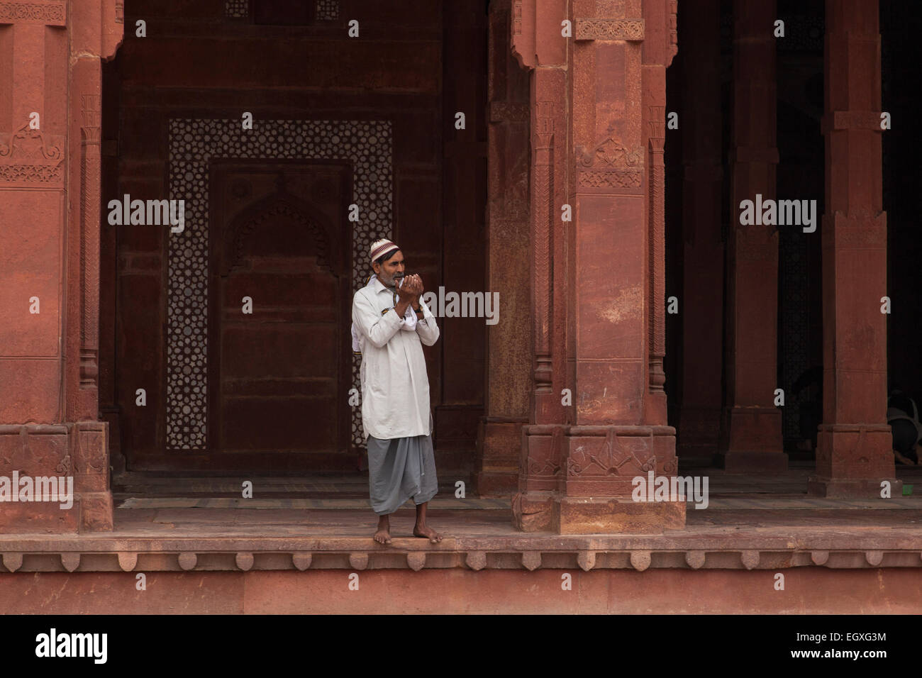 Uomo musulmano in piedi da una colonna di Fatehpur Sikri, Uttar Pradesh, India Foto Stock