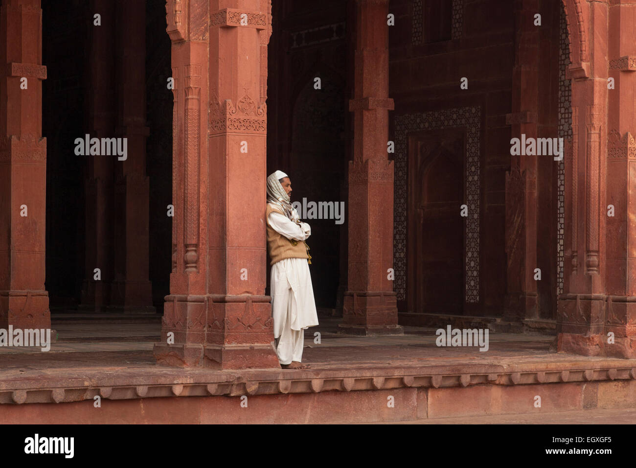 Uomo musulmano in piedi da una colonna di Fatehpur Sikri, Uttar Pradesh, India Foto Stock