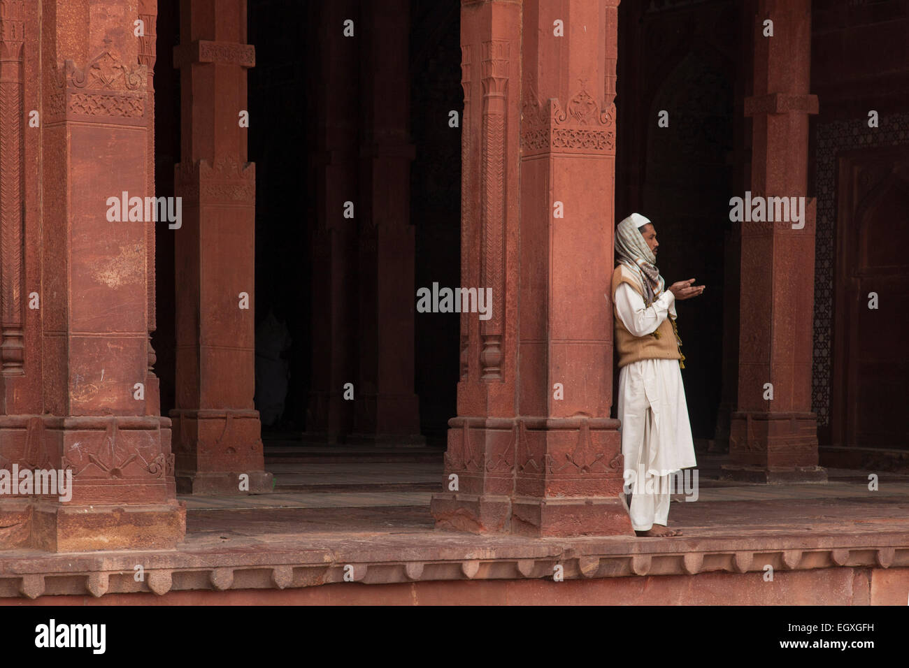 Uomo musulmano in piedi da una colonna di Fatehpur Sikri, Uttar Pradesh, India Foto Stock
