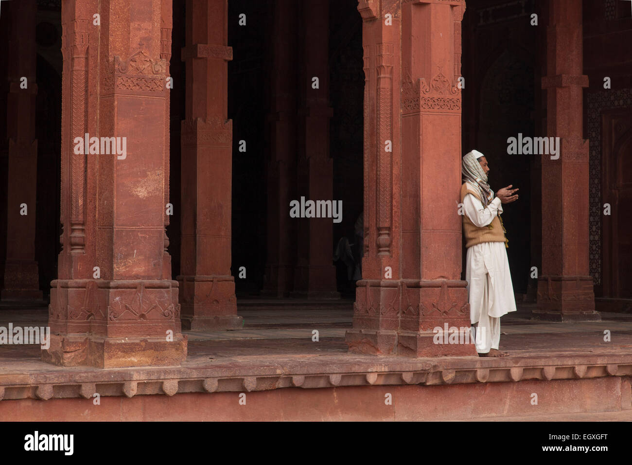 Uomo musulmano in piedi da una colonna di Fatehpur Sikri, Uttar Pradesh, India Foto Stock