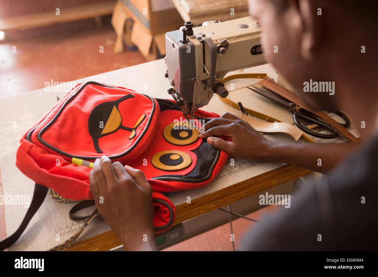 Un artigiano cuce un sacco di scuola in un workshop a Dar es Salaam, Tanzania Africa Orientale. Foto Stock