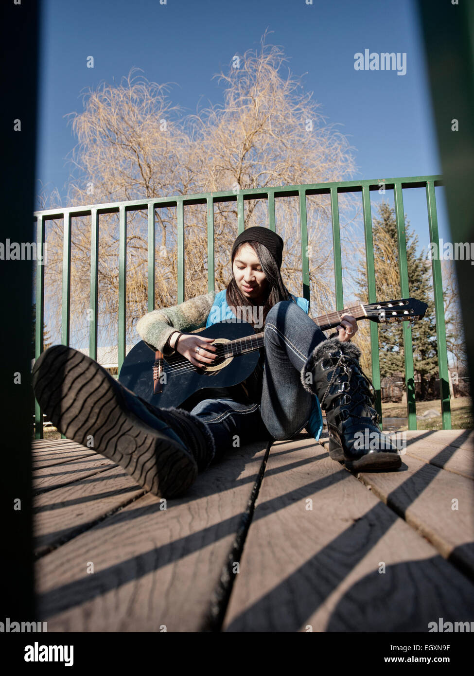 Un adulto teen donna siede su un piccolo passaggio pedonale e suona la chitarra. Foto Stock