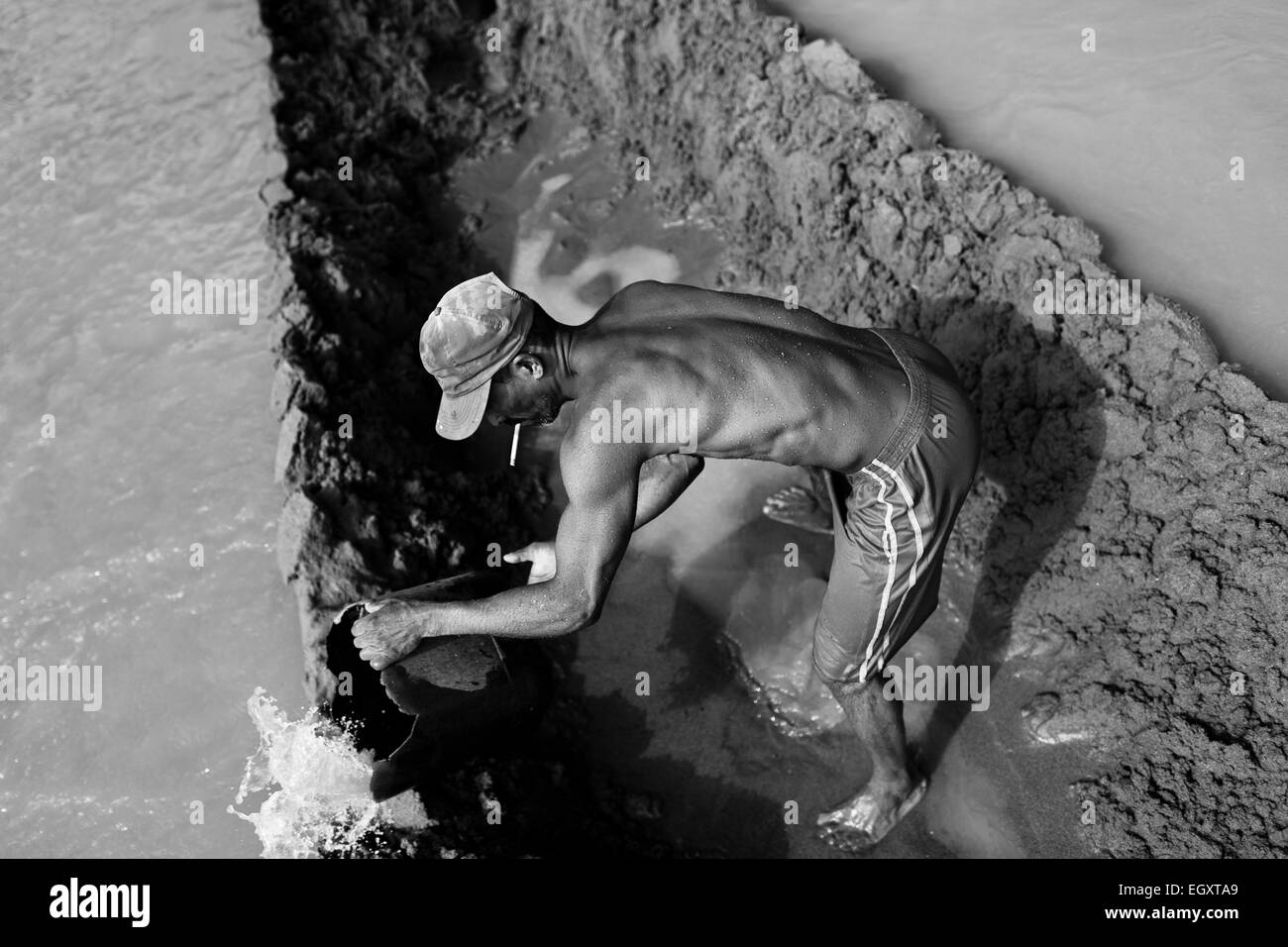 Un colombiano sabbia miner bails l'acqua fuori della barca ancorata nel mezzo del fiume La Vieja in Cartago, Colombia. Foto Stock