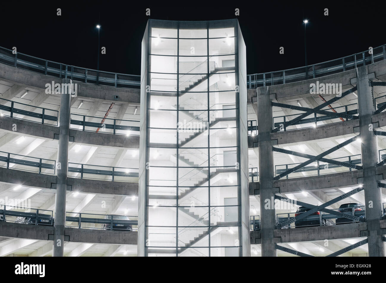 Automobili parcheggiate nel parcheggio illuminato garage struttura in calcestruzzo di notte Foto Stock