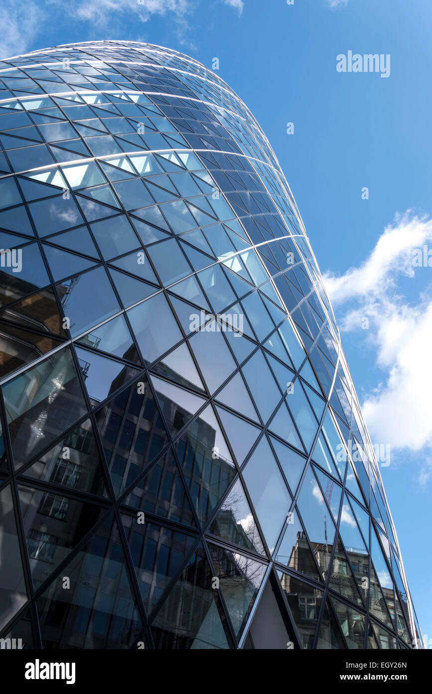 Le riflessioni di altri edifici nel London Gherkin contro principalmente un cielo blu Foto Stock