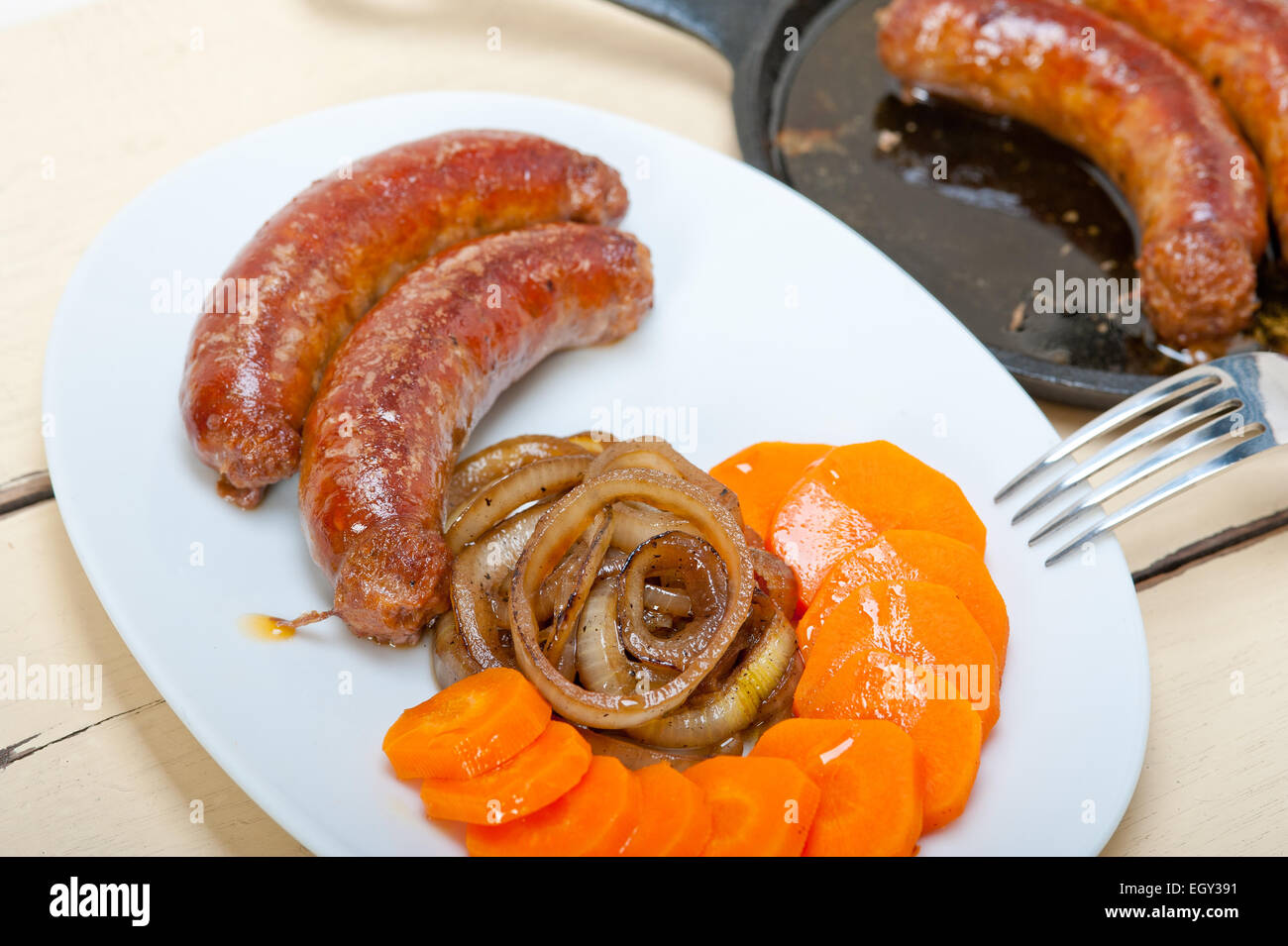 Salsicce di manzo cotto in padella di ferro con la carota e la cipolla Foto Stock