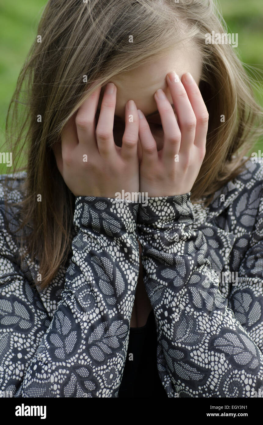 Giovane donna testa in mani piangendo all'aperto Foto Stock