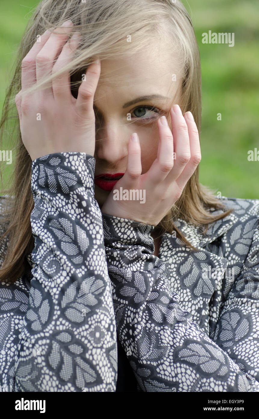 Spaventata giovane donna nasconde il viso con le mani alla ricerca di distanza Foto Stock
