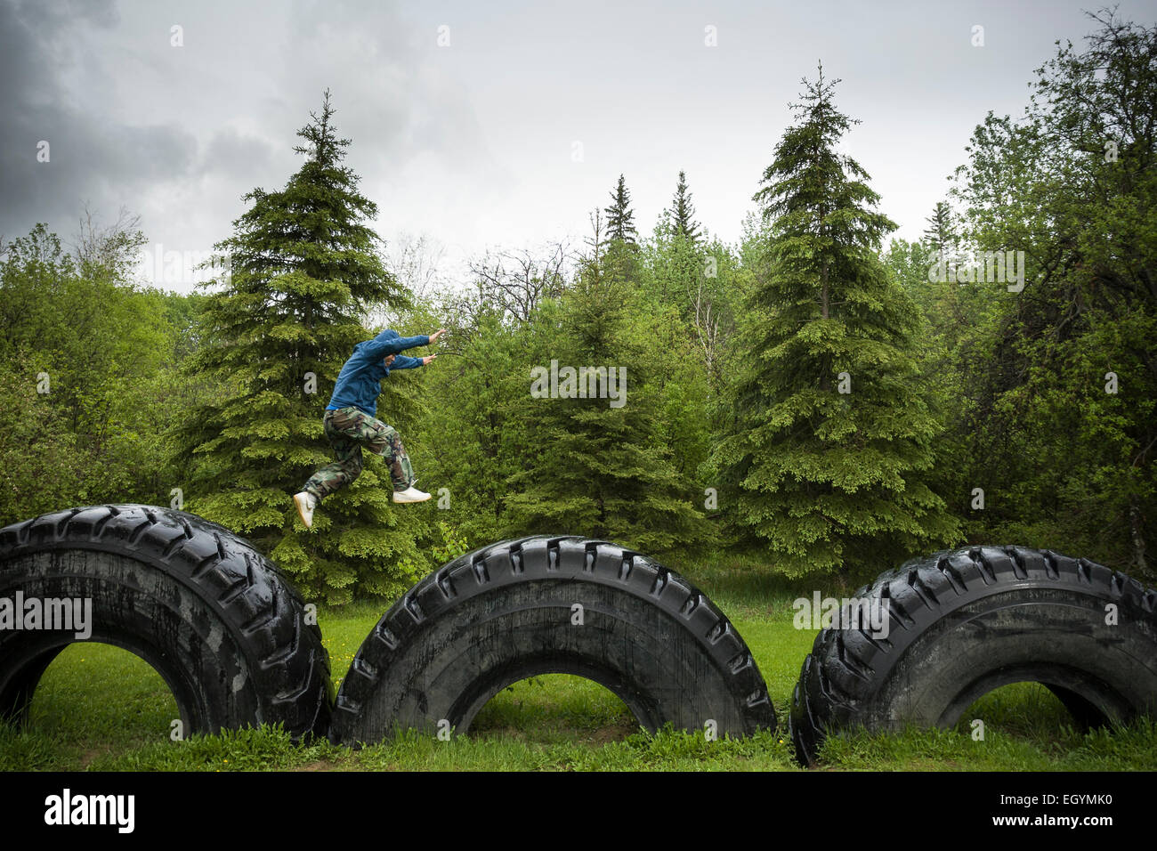 Un giovane di Anzac, Alberta, salti da gigante pneumatico al gigante pneumatico, i segnali dello sviluppo industriale della regione. Foto Stock