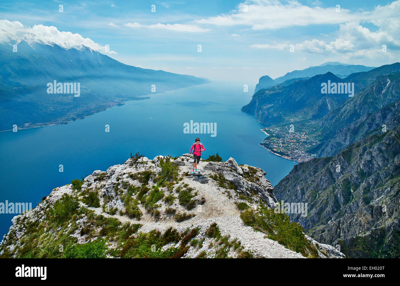L'Italia, Trentino, donna in esecuzione sul picco di montagna al lago di Garda Foto Stock