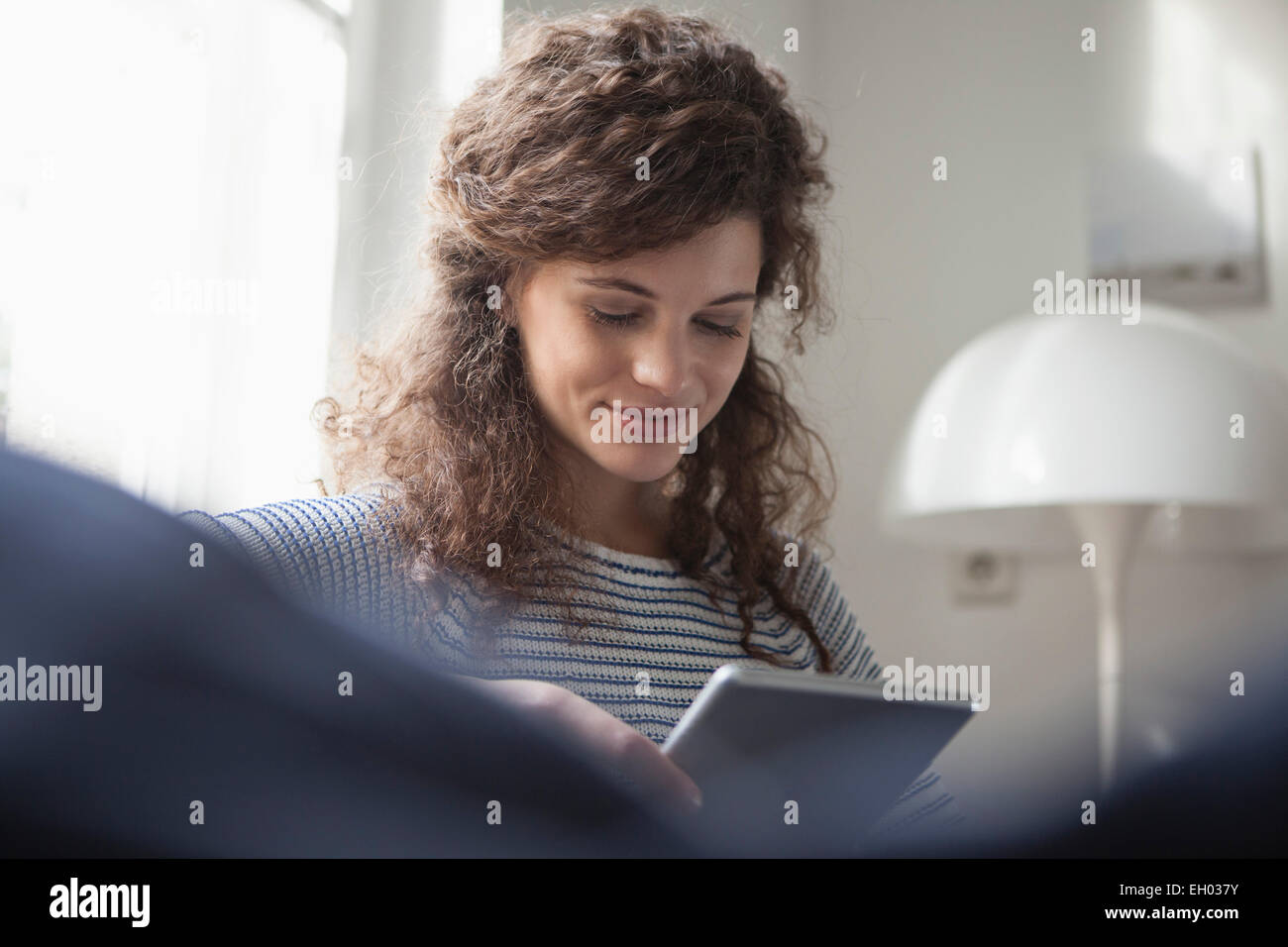 Giovane donna di casa utilizzando tavoletta digitale Foto Stock
