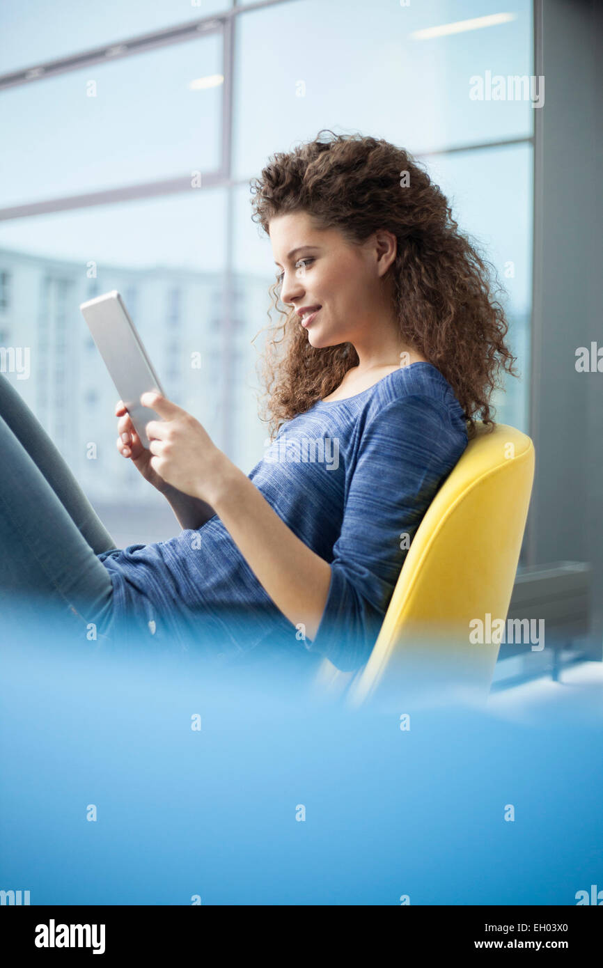 Sorridente giovane donna con tavoletta digitale in corrispondenza della finestra Foto Stock