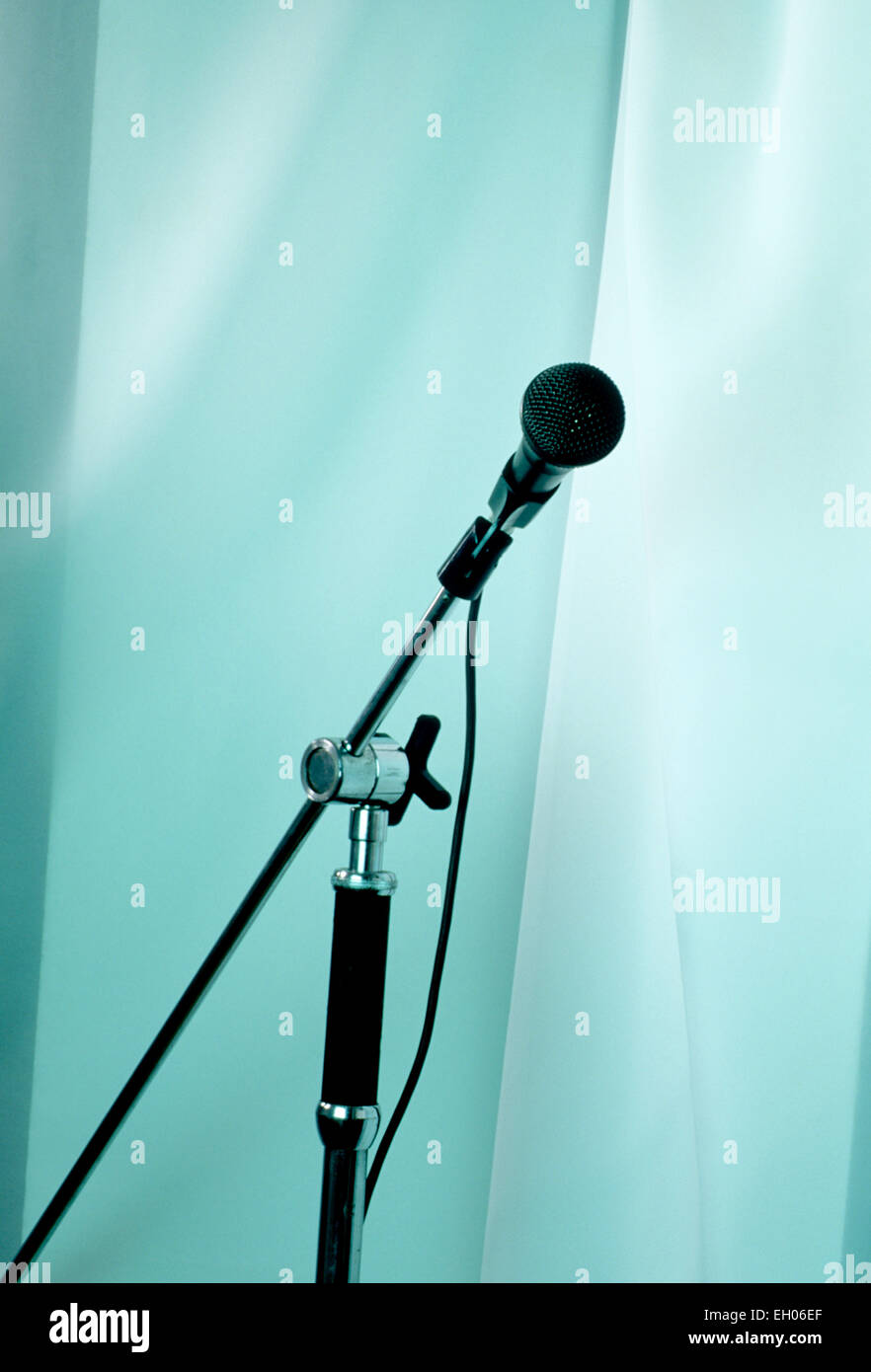 Ancora vita immagine di un microfono e di un supporto contro un morbido blu tenda colorata Foto Stock