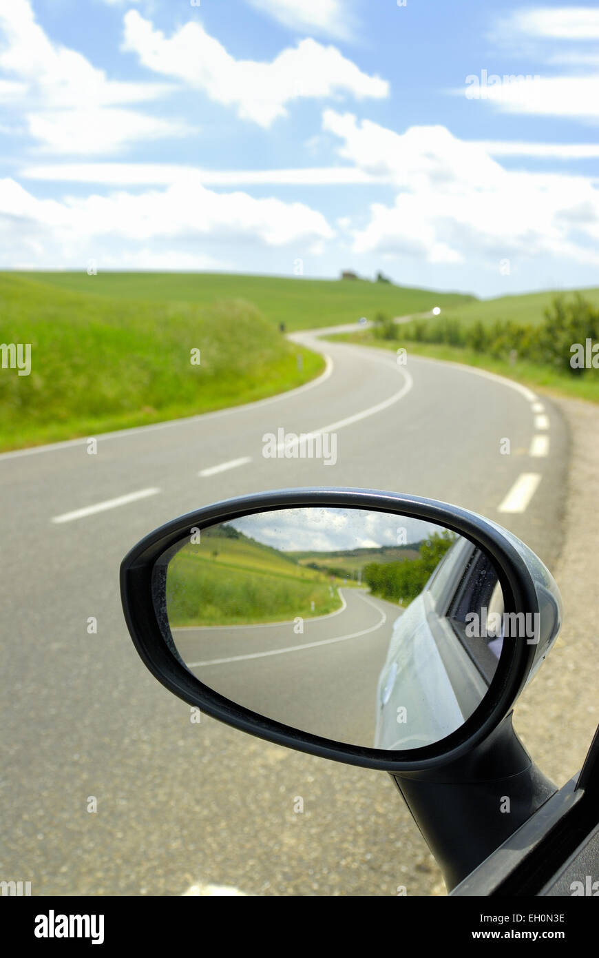 Specchio retrovisore di auto e strada tortuosa, Toscana, Italia Foto Stock