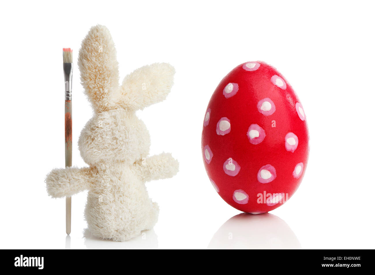 Farcite coniglietto pasquale per vernici in rosso di un uovo di pasqua davanti a uno sfondo bianco Foto Stock