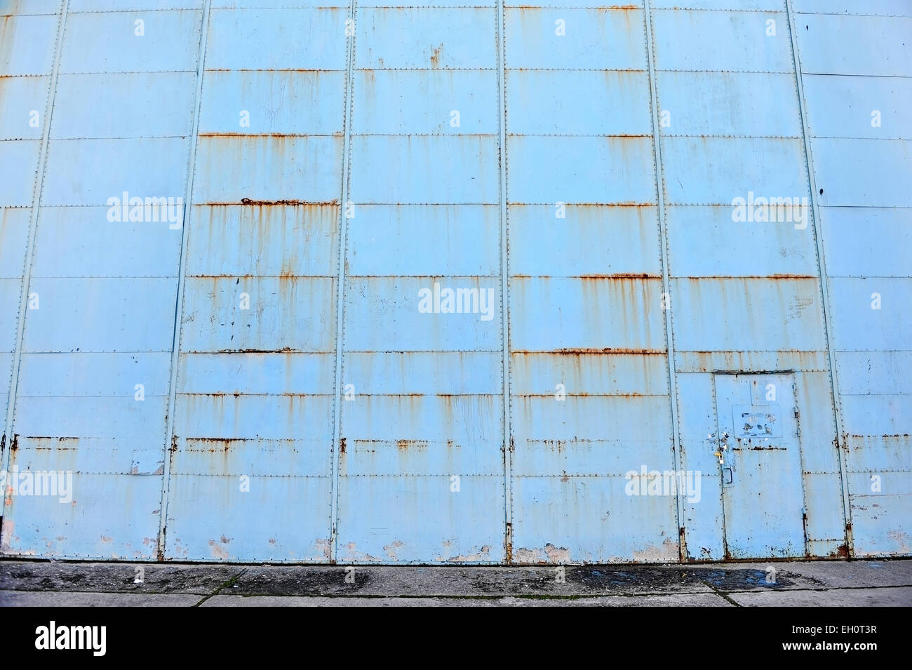 Ripresa industriale con un blu e vecchio arrugginito cancello hangar Foto Stock