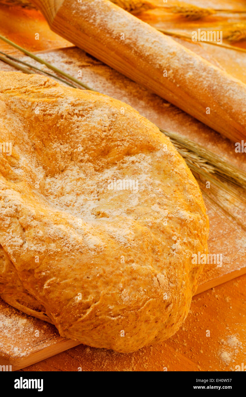 Primo piano di una pasta fatta in casa su un tavolo di legno con alcune spighe di grano ed un perno di laminazione Foto Stock