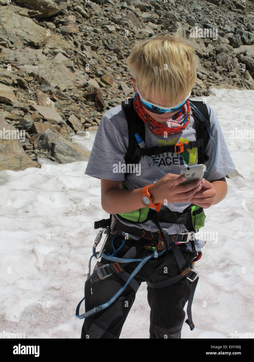 Tecnologia mobile essendo utilizzato da un giovane ragazzo su una scalata e alpinismo spedizione Foto Stock