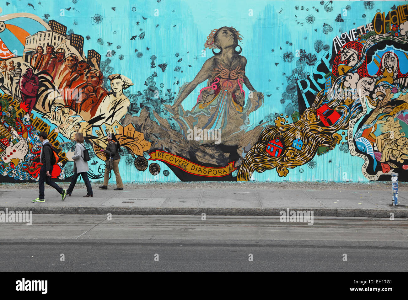 I newyorkesi camminano per lavorare oltre un murale colorato installato da Swoon sul Muro del Mural Bowery su Houston Street nella parte inferiore Foto Stock