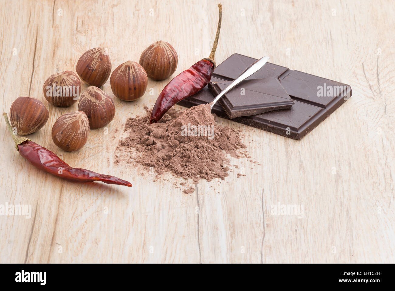 Una vista frontale di chili di cioccolato, nocciole,chili e coperto di cucchiaino di cacao. Foto Stock