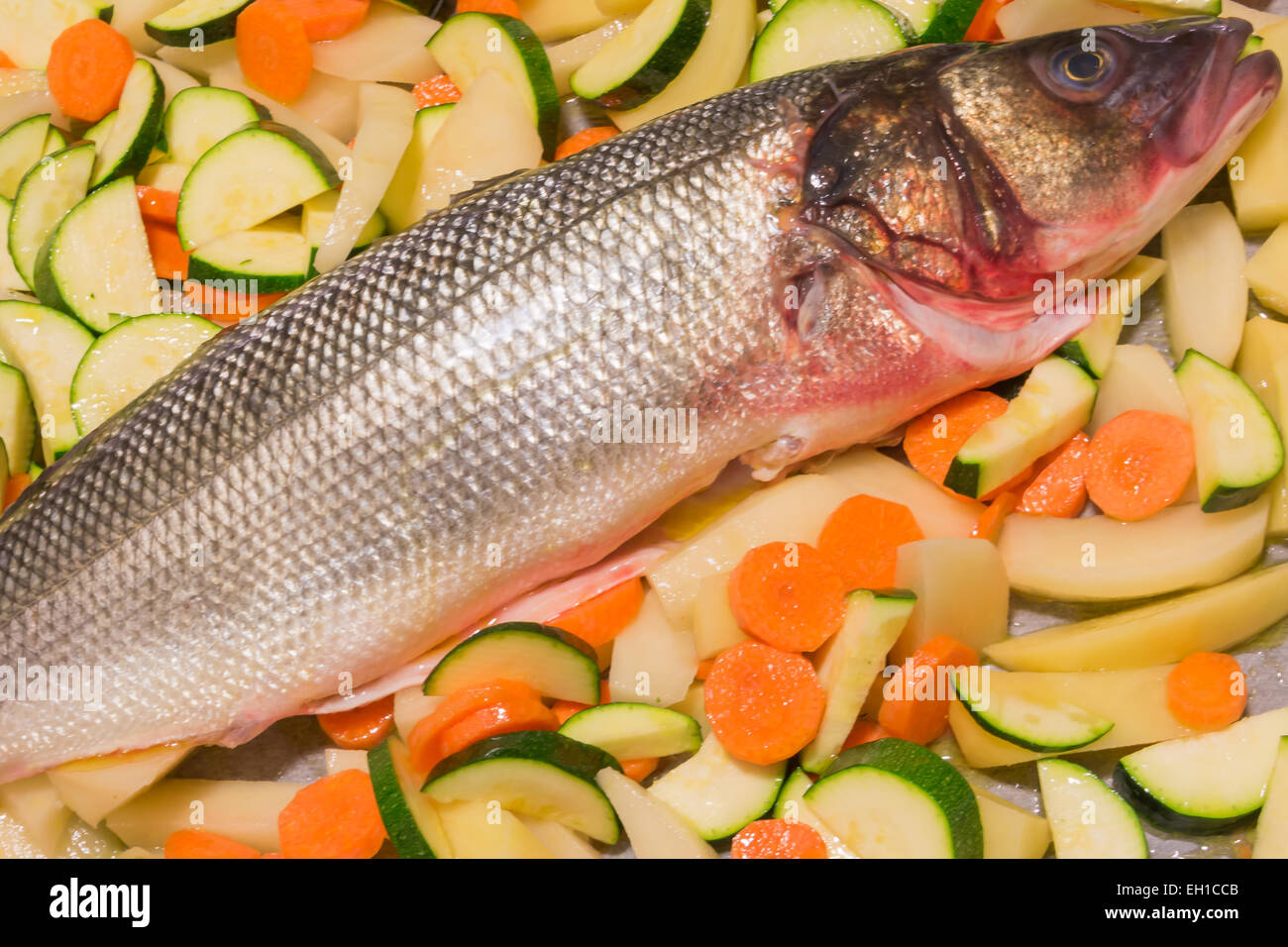 Materie spigola pesce con fette di patate, carote e zucchine prima di home-cotta Foto Stock